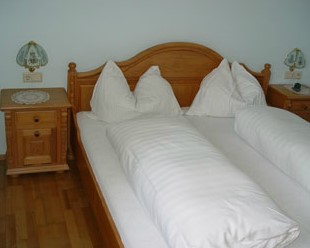 Doppelbett mit weißen Bettdecken und einem Kopfteil aus Holz