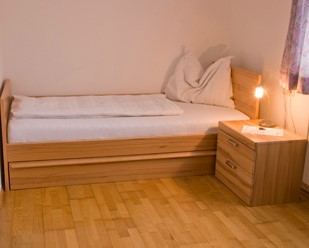 Einzelbett aus Holz mit Nachttisch und Leselampe