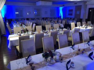 Saal mit festlich gedeckten Tischen und blauer Abendbeleuchtung